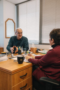 Two Researcher seated across office table engaged in conversation