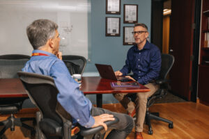 Two people seated by office table engaged in a conversation