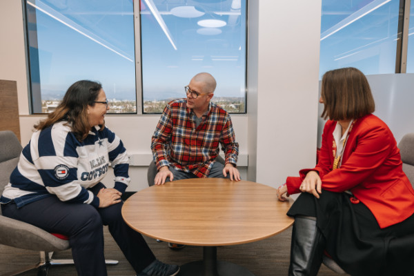 Group of three people chatting by round coffee table